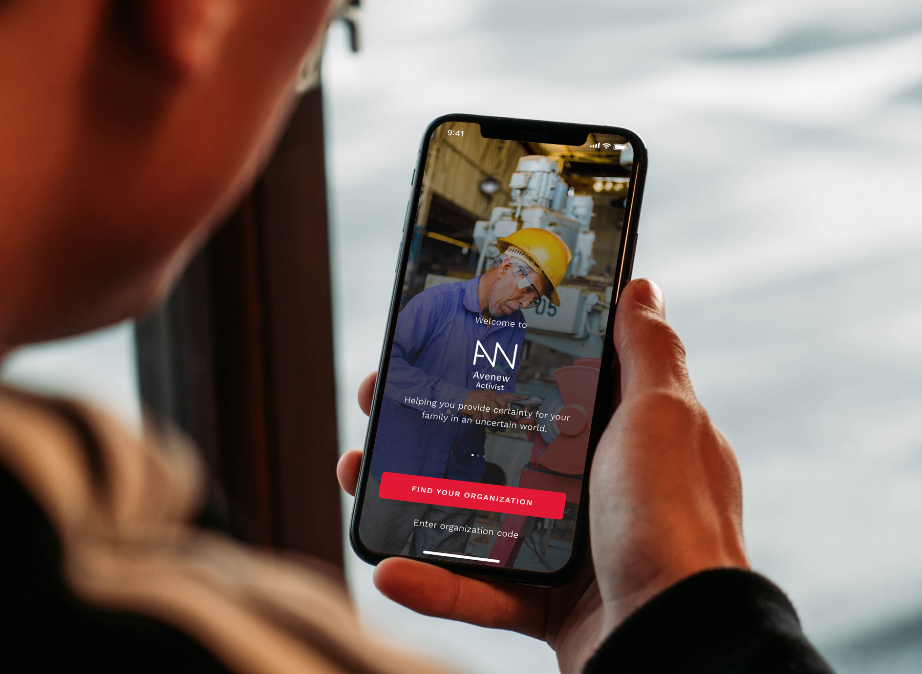 Hand holding a phone showing the Avenew app's find-your-organization screen